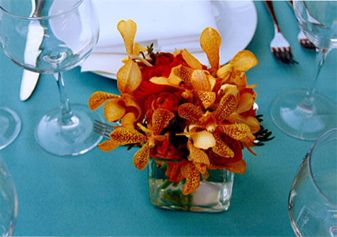 Her long table centerpiece alternated orange orchid bunches in square glass