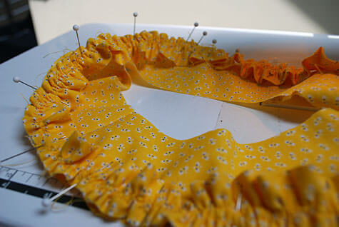 Pinning a ruffle on a baby bonnet hat