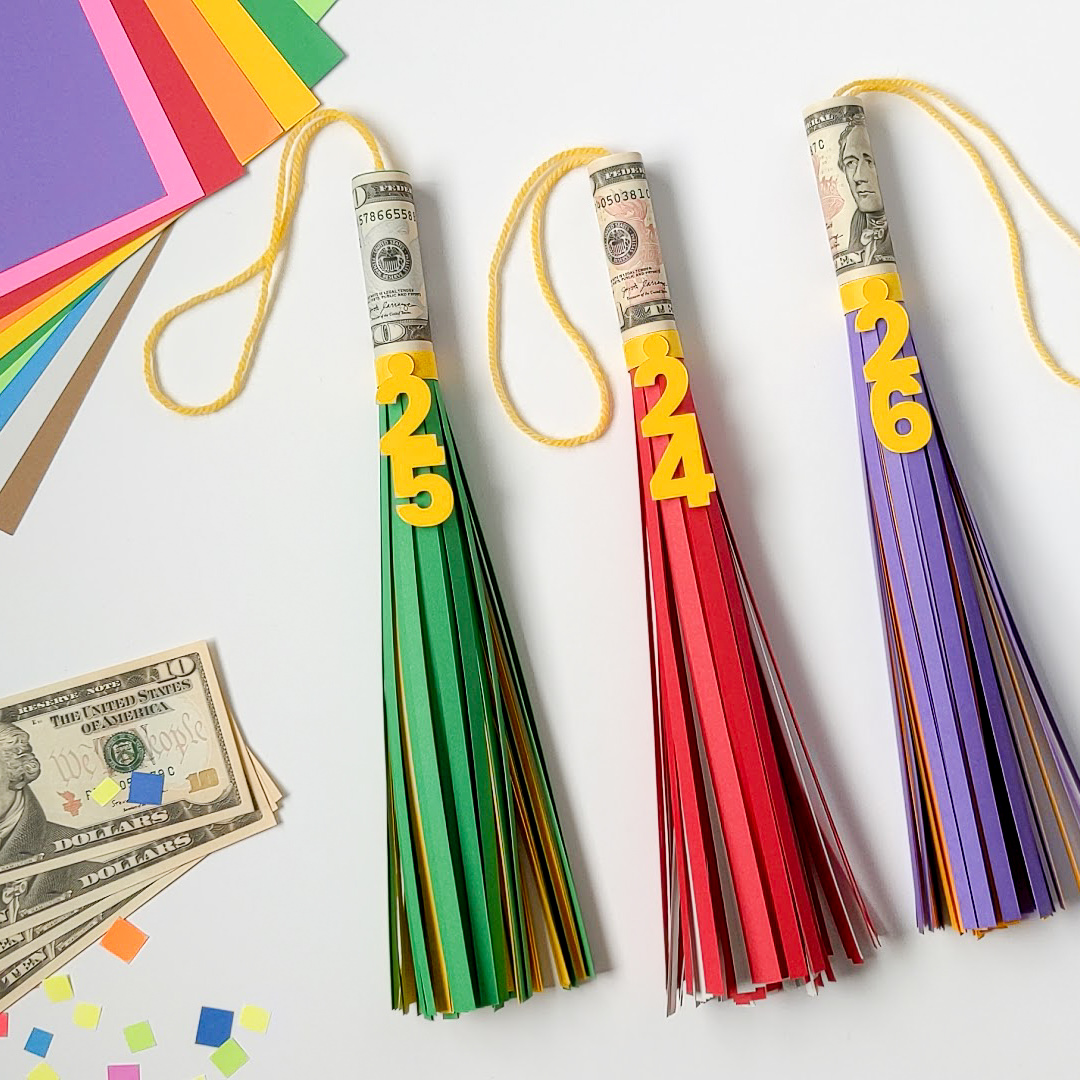 Three big paper graduation tassels with cash rolled inside for a money graduation gift