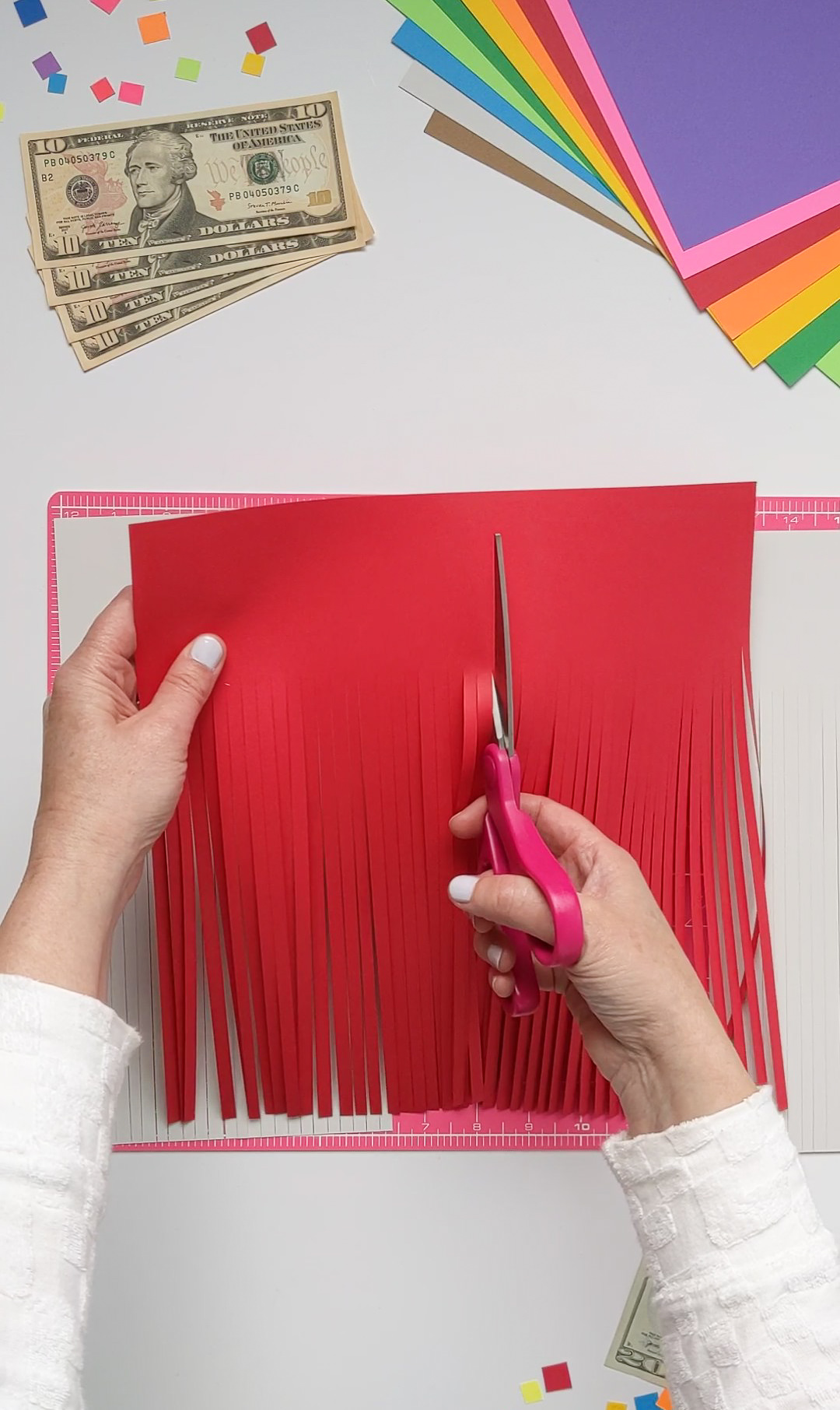 Cutting paper fringe in half to create multi-color DIY graduation tassels