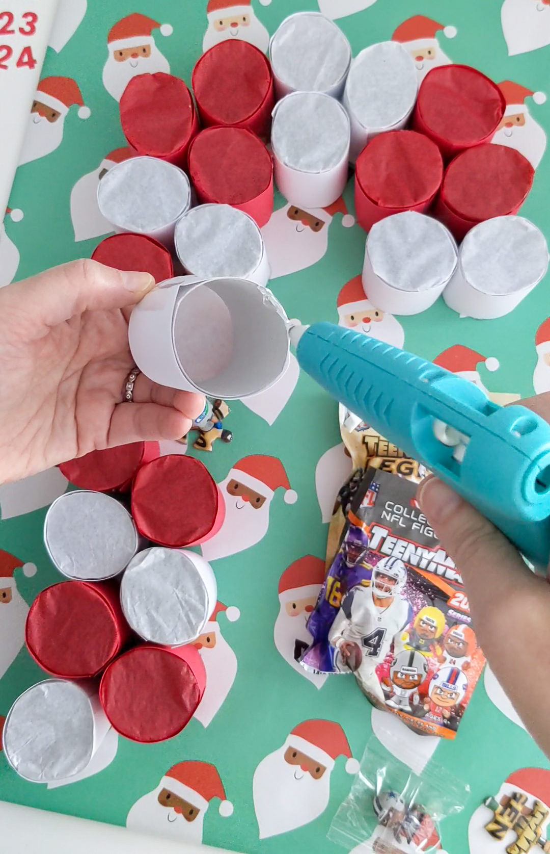 Gluing toilet paper roll tubes to a cardboard base to make a DIY advent calendar for small toys