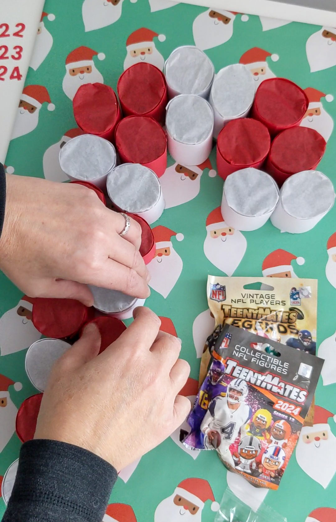 Gluing toilet paper roll tubes to a cardboard base to make a DIY advent calendar for small toys