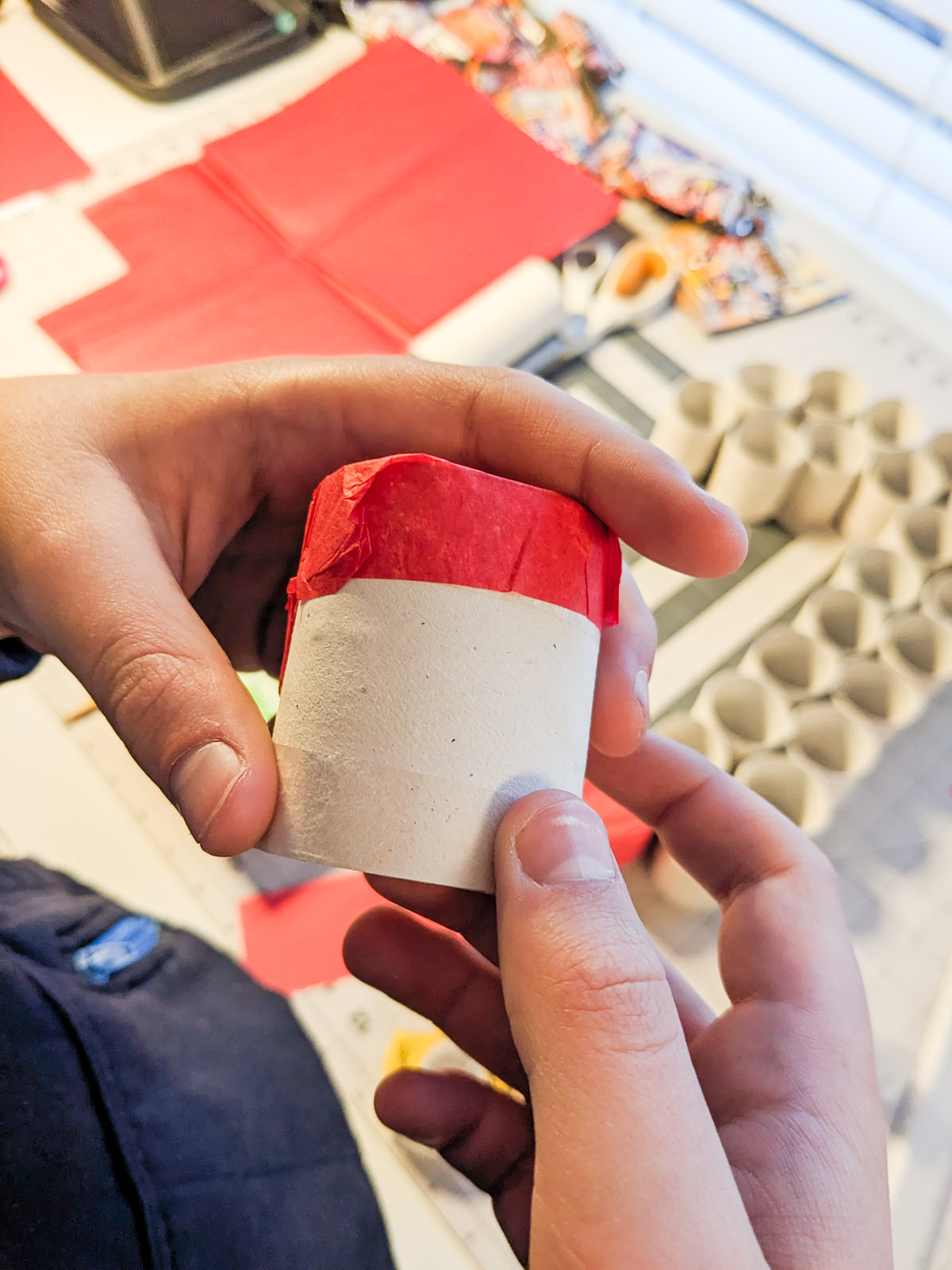 Wrapping tissue paper around the end of cardboard toilet paper tubes to make a DIY advent calendar