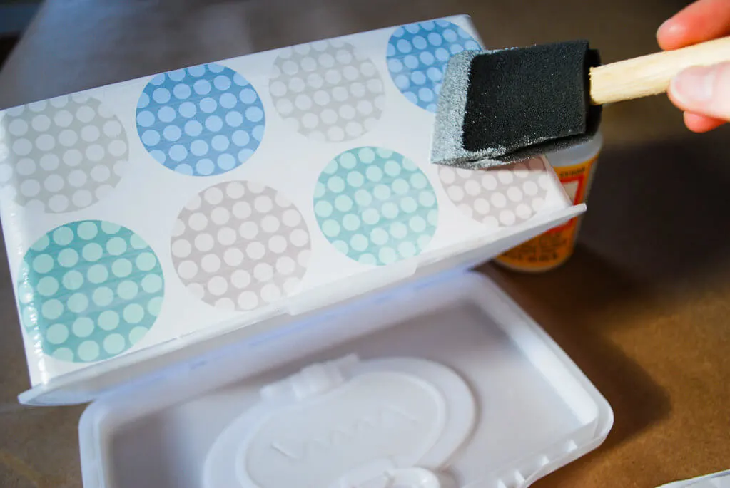 Brushing Mod Podge onto baby wipes box