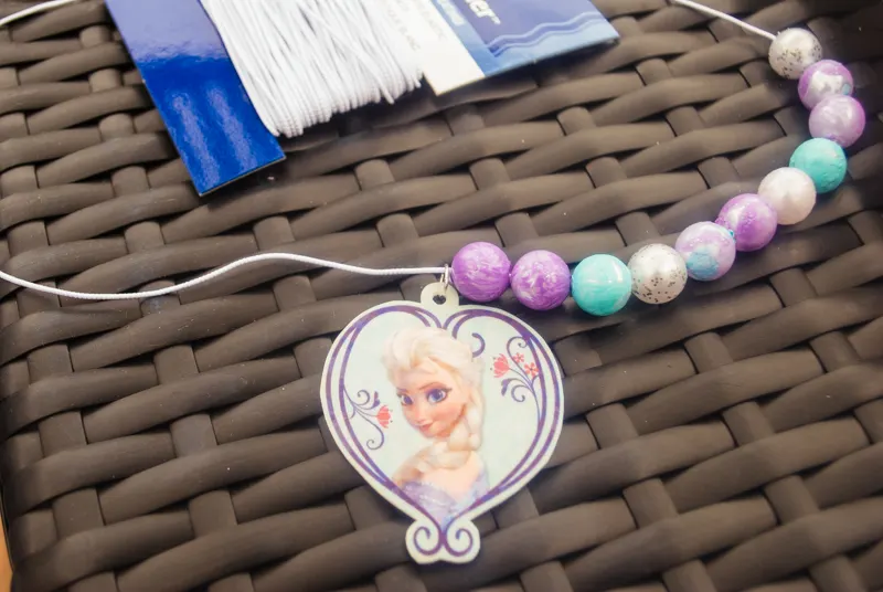 DIY Frozen beaded necklace craft for Frozen birthday parties and Elsa Halloween costumes. Print Elsa onto Shrinky Dinks plastic and bake, then paint beads and string. Such a cute kids activity for summertime, rainy days or a Frozen birthday party!