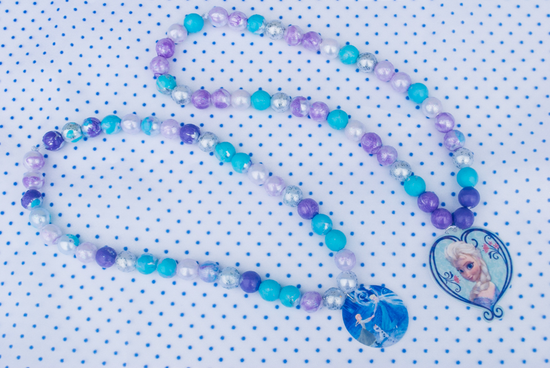 DIY Frozen beaded necklace craft for Frozen birthday parties and Elsa Halloween costumes. Print Elsa onto Shrinky Dinks plastic and bake, then paint beads and string. Such a cute kids activity for summertime, rainy days or a Frozen birthday party!