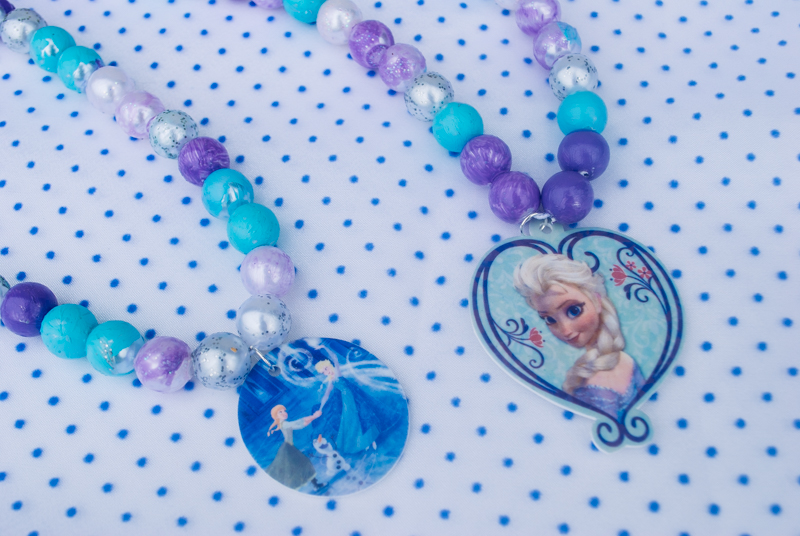 DIY Frozen beaded necklace craft for Frozen birthday parties and Elsa Halloween costumes. Print Elsa onto Shrinky Dinks plastic and bake, then paint beads and string. Such a cute kids activity for summertime, rainy days or a Frozen birthday party!