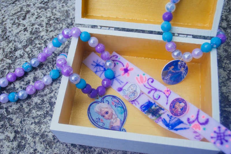 DIY Frozen beaded necklace craft for Frozen birthday parties and Elsa Halloween costumes. Print Elsa onto Shrinky Dinks plastic and bake, then paint beads and string. Such a cute kids activity for summertime, rainy days or a Frozen birthday party!