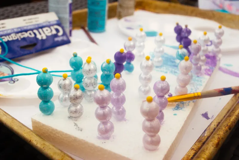 DIY Frozen beaded necklace craft for Frozen birthday parties and Elsa Halloween costumes. Print Elsa onto Shrinky Dinks plastic and bake, then paint beads and string. Such a cute kids activity for summertime, rainy days or a Frozen birthday party!