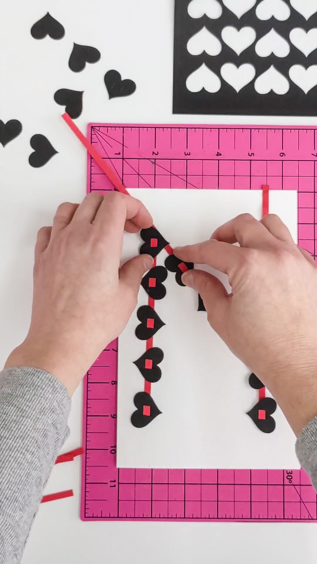 Gluing black hearts onto a DIY Valentine's Day card