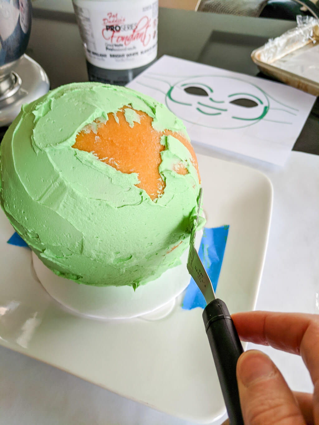 Icing buttercream frosting onto a dome ball sphere cake
