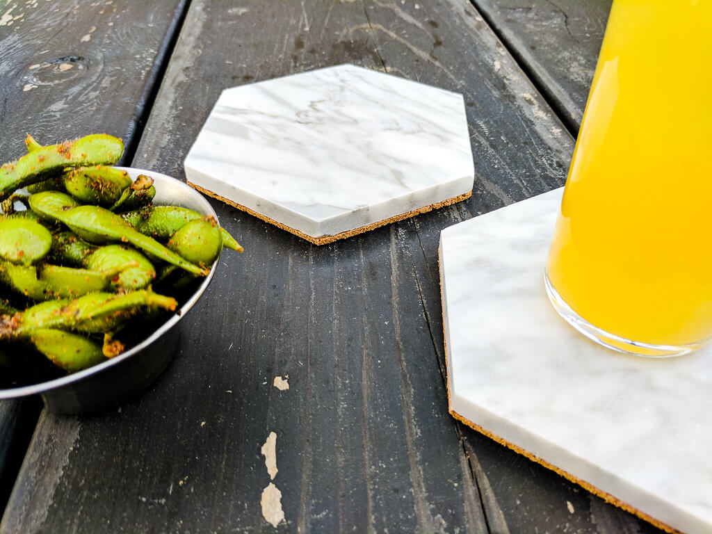 Easy DIY hexagon Carrara marble coasters. So easy and less than $5 each, makes a great DIY gift! Just add cork to backs of hexagon bathroom tiles using Mod Podge, optionally seal. [easy DIY gift | DIY coasters | marble coasters | cork coasters | easy Mother's Day DIY gift | easy DIY Christmas gift | easy DIY housewarming gift]