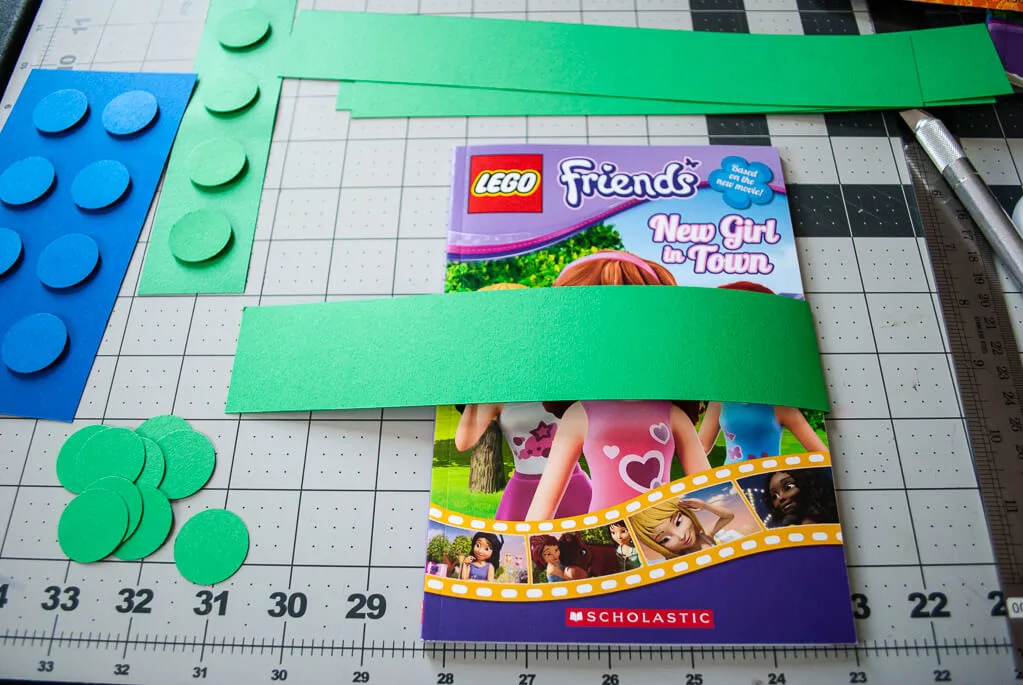 Wrap paper around a LEGO book to make a book sleeve on the LEGO birthday party favor
