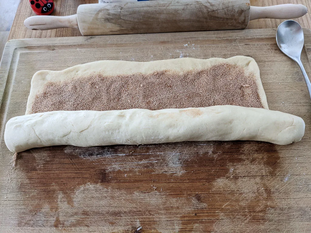 Rolling cinnamon roll King Cake dough