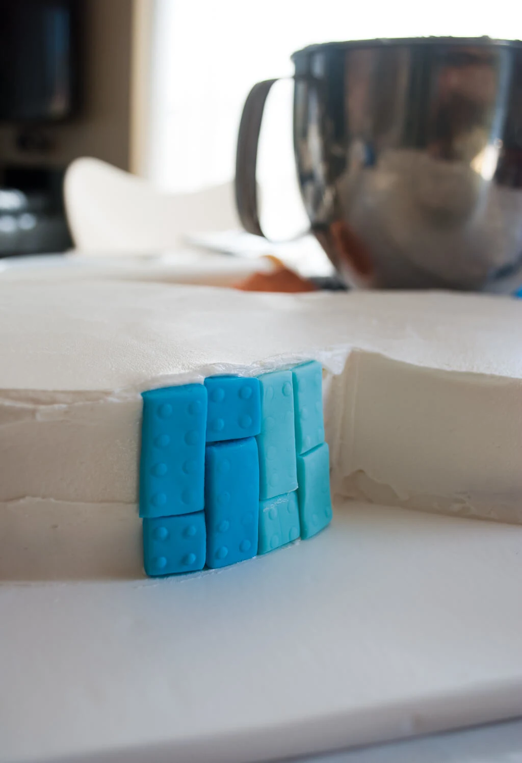 Putting fondant LEGO bricks onto a birthday cake