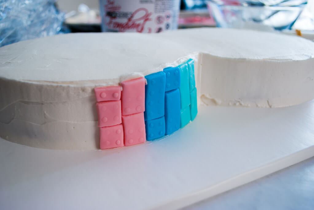 Putting fondant LEGO bricks onto a birthday cake