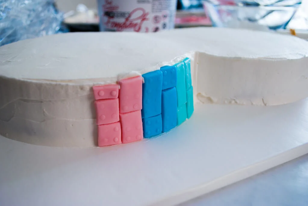 Putting fondant LEGO bricks onto a birthday cake