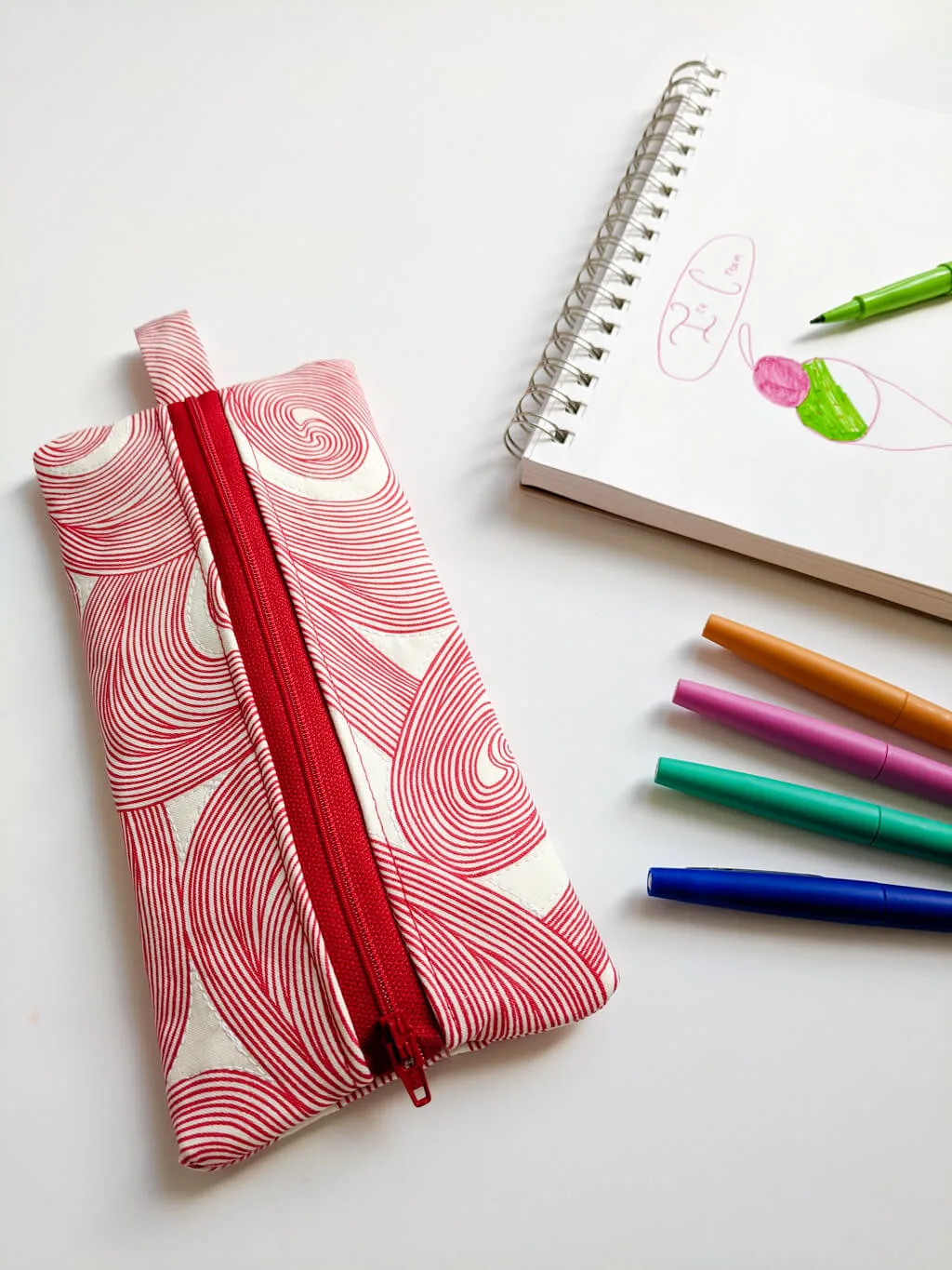 DIY zipper pencil case next to a drawing and pens
