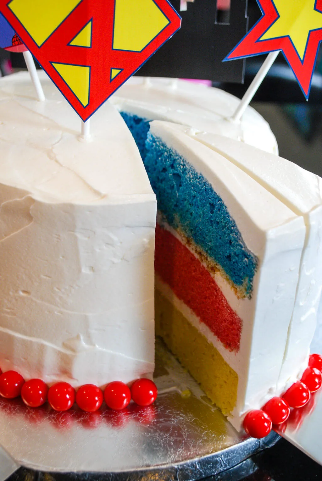 Superhero cake with colorful cake layers in yellow, red, and blue