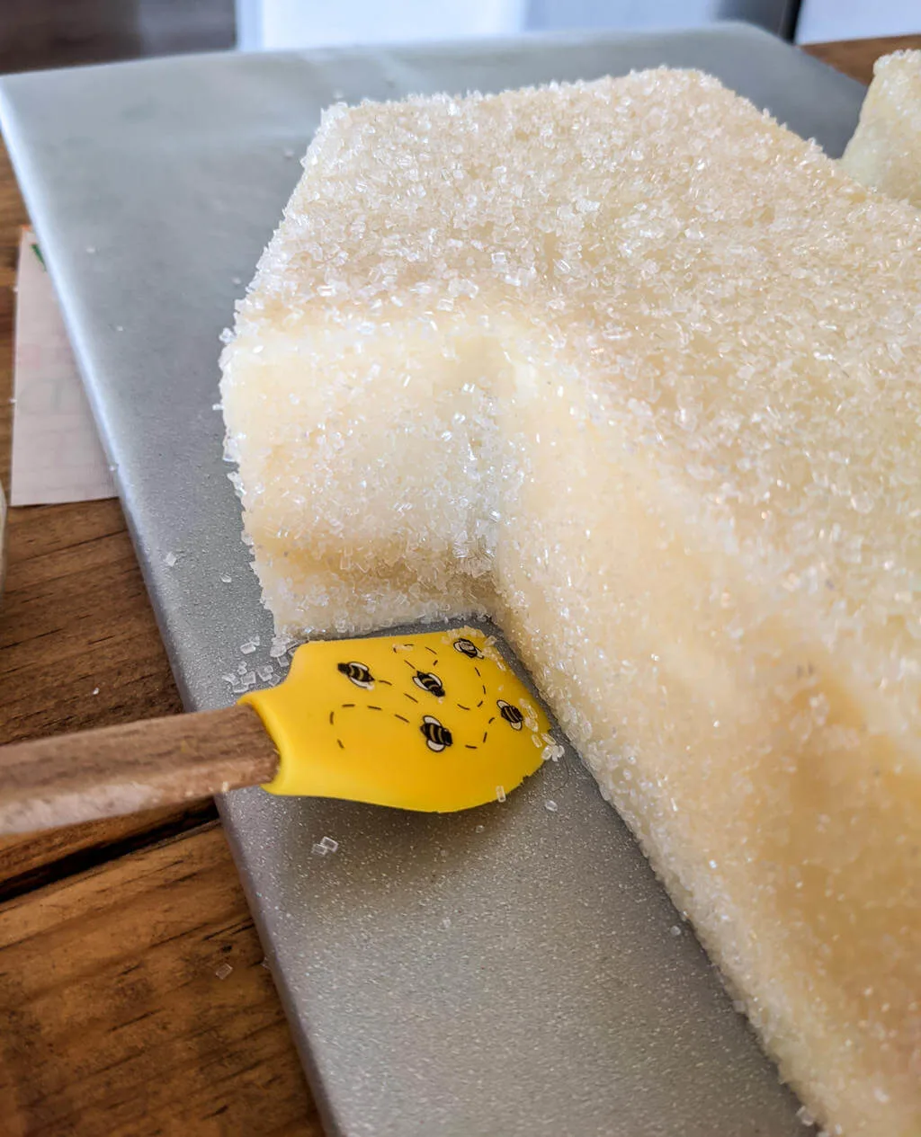 Using a spatula to clean sanding sugar from cake board