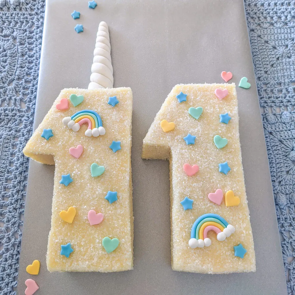 Age 11 unicorn birthday cake with fondant horn, rainbows, stars, and hearts