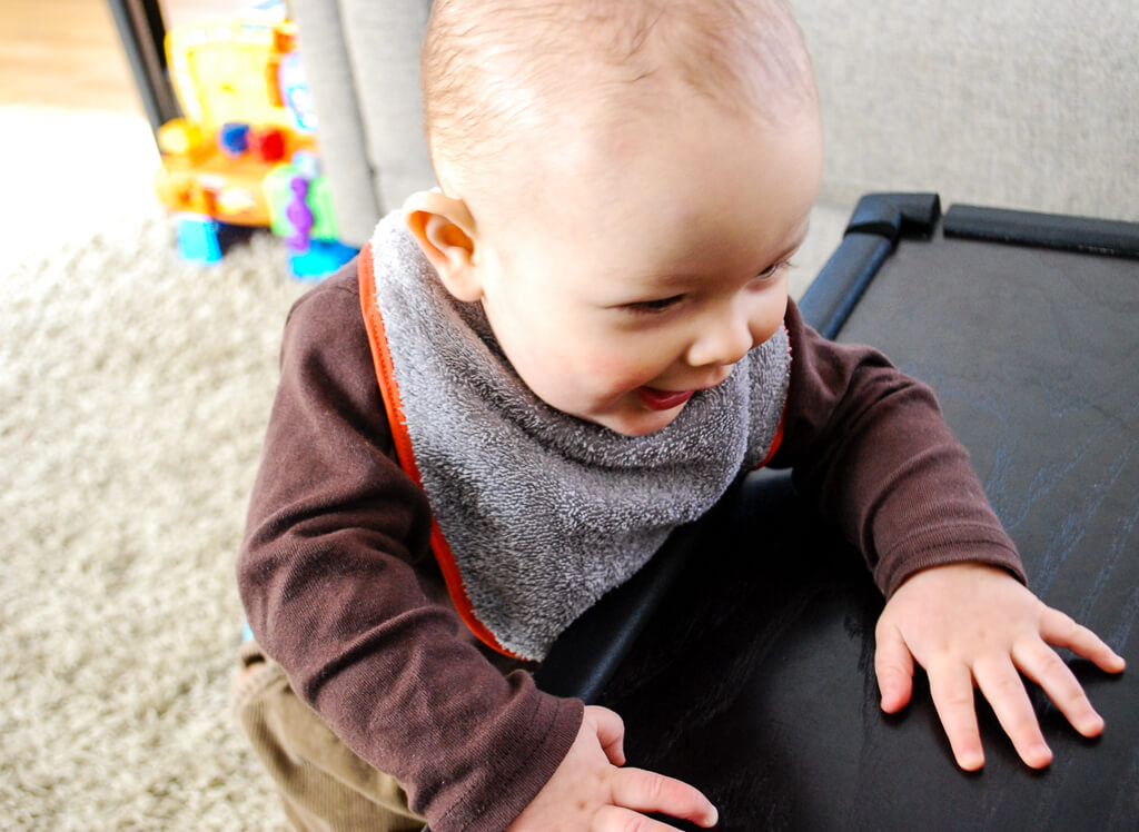 Happy baby wearing a DIY free baby bib sewing pattern that's lined and made with terry cloth to prevent wet cloths and chapped skin from drooly teething babies