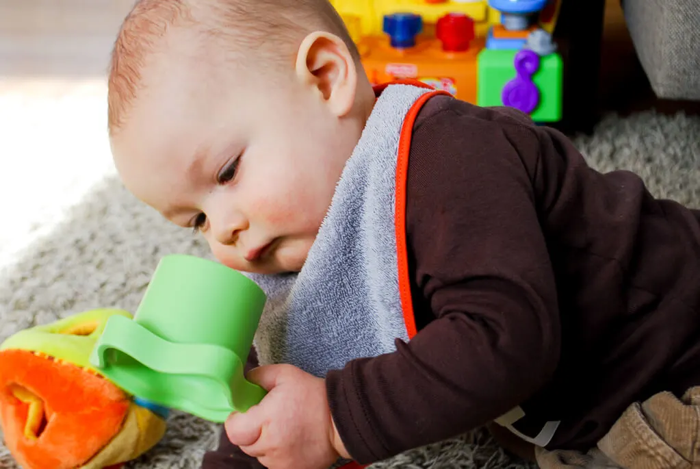 Curious baby wearing a DIY free baby bib sewing pattern that's lined and made with terry cloth to prevent wet cloths and chapped skin from drooly teething babies