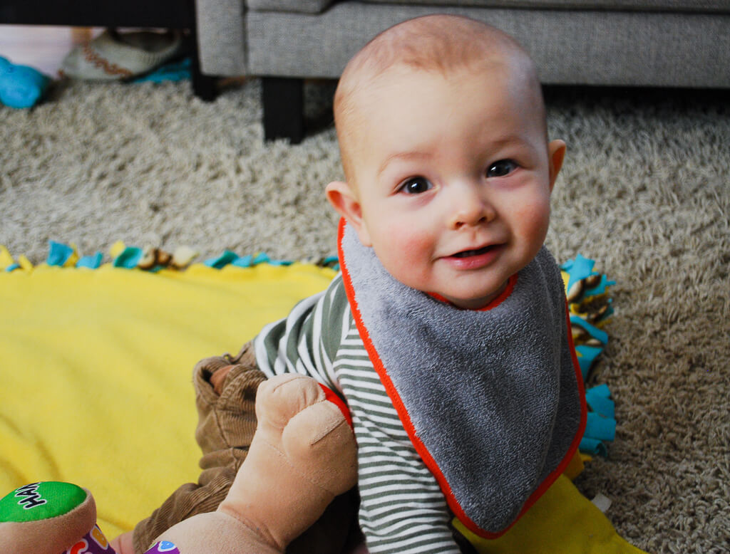 Happy baby wearing a DIY free baby bib sewing pattern that's lined and made with terry cloth to prevent wet cloths and chapped skin from drooly teething babies