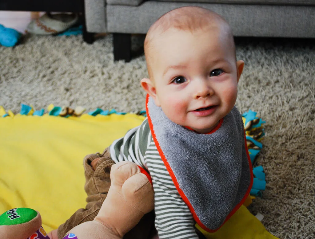 Happy baby wearing a DIY free baby bib sewing pattern that's lined and made with terry cloth to prevent wet cloths and chapped skin from drooly teething babies