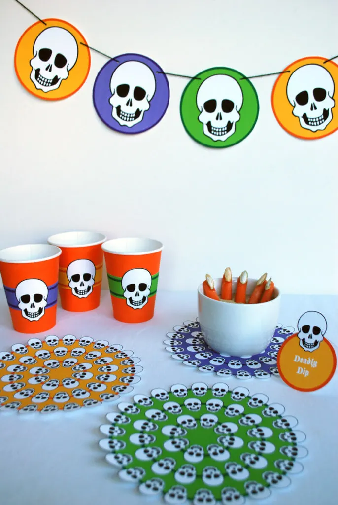 Free printable skeleton Halloween table decorations - banner, cup wraps, food labels and doilies in orange, purple, green and yellow