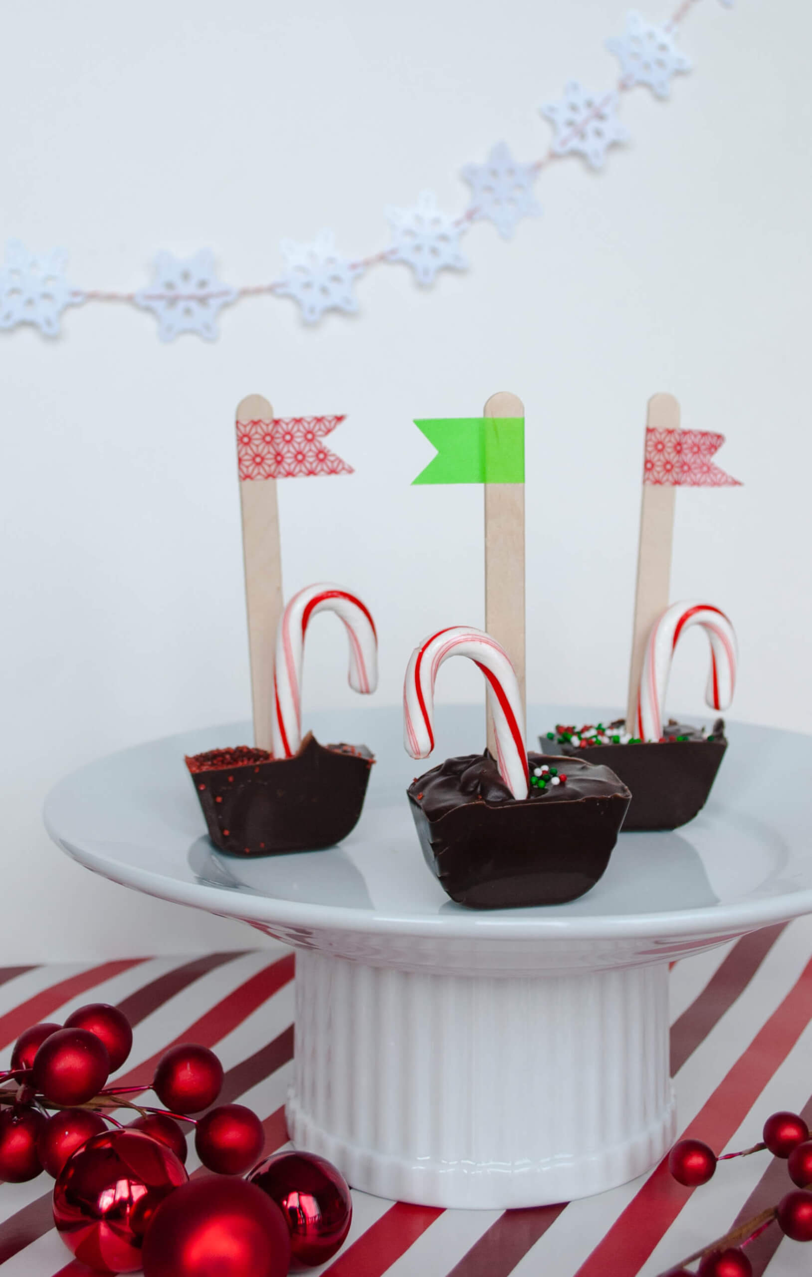 Handmade chocolate and peppermint stir sticks going into mug of cocoa