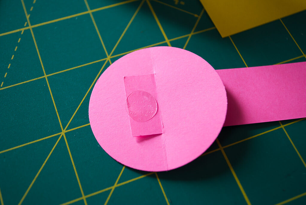 Putting a glue dot on a paper basket handle