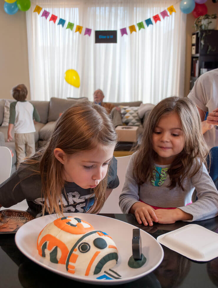 Blowing out candles on a Star Wars birthday cake