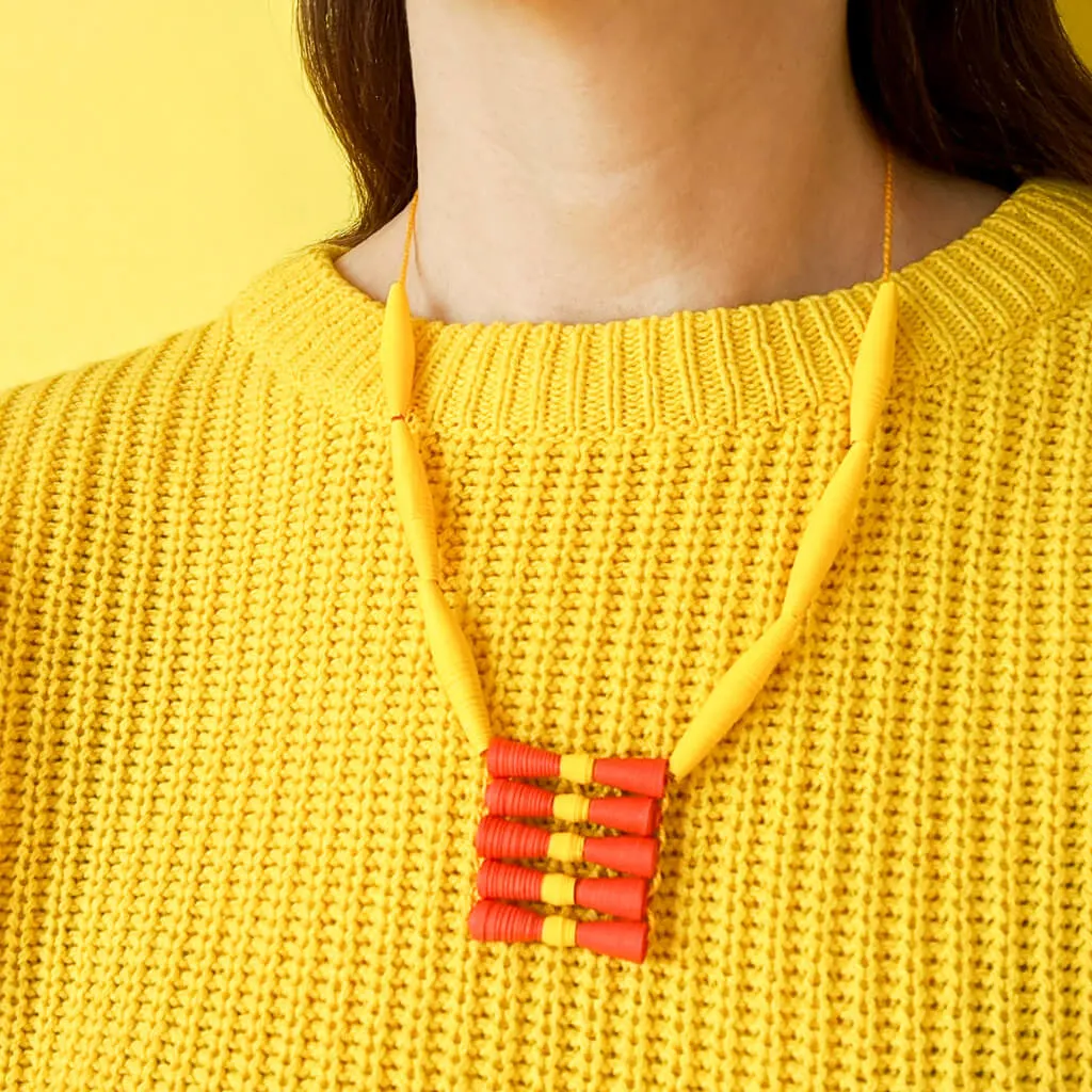 Paper bead necklace with yellow sweater