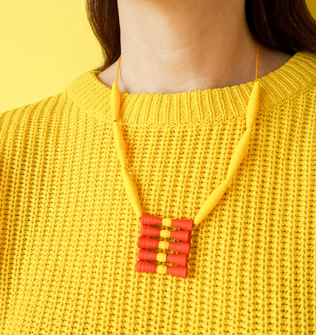 Paper bead necklace with yellow sweater