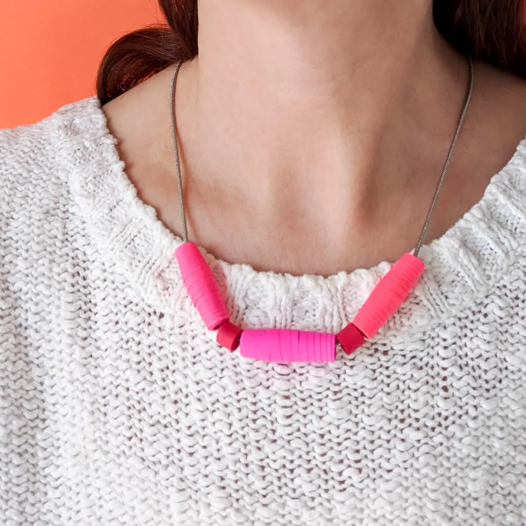 DIY paper bead necklace in pink and red worn with white sweater