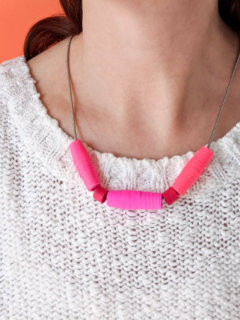 DIY paper bead necklace in pink and red worn with white sweater