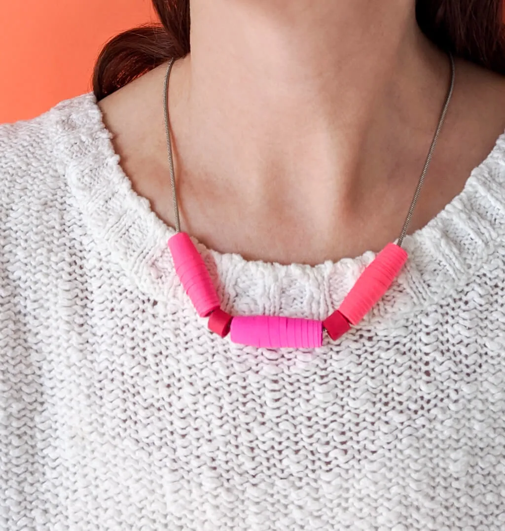 DIY paper bead necklace in pink and red worn with white sweater