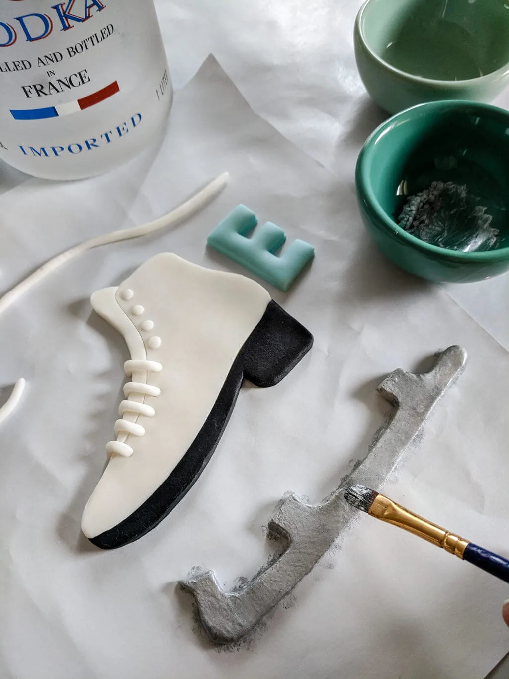 How to paint silver luster dust onto fondant to make an easy fondant ice skate cake topper. Use this free ice skate cake topper template printable to make an ice skating cake with step-by-step photos and images. #ice #skating #cake #skate #fondant #topper Painting silver luster dust onto fondant