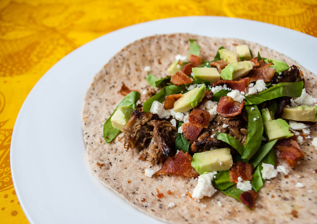 Easy pork tacos recipe in the slow cooker - top it with bacon, avocado, queso fresco, and kale or spinach