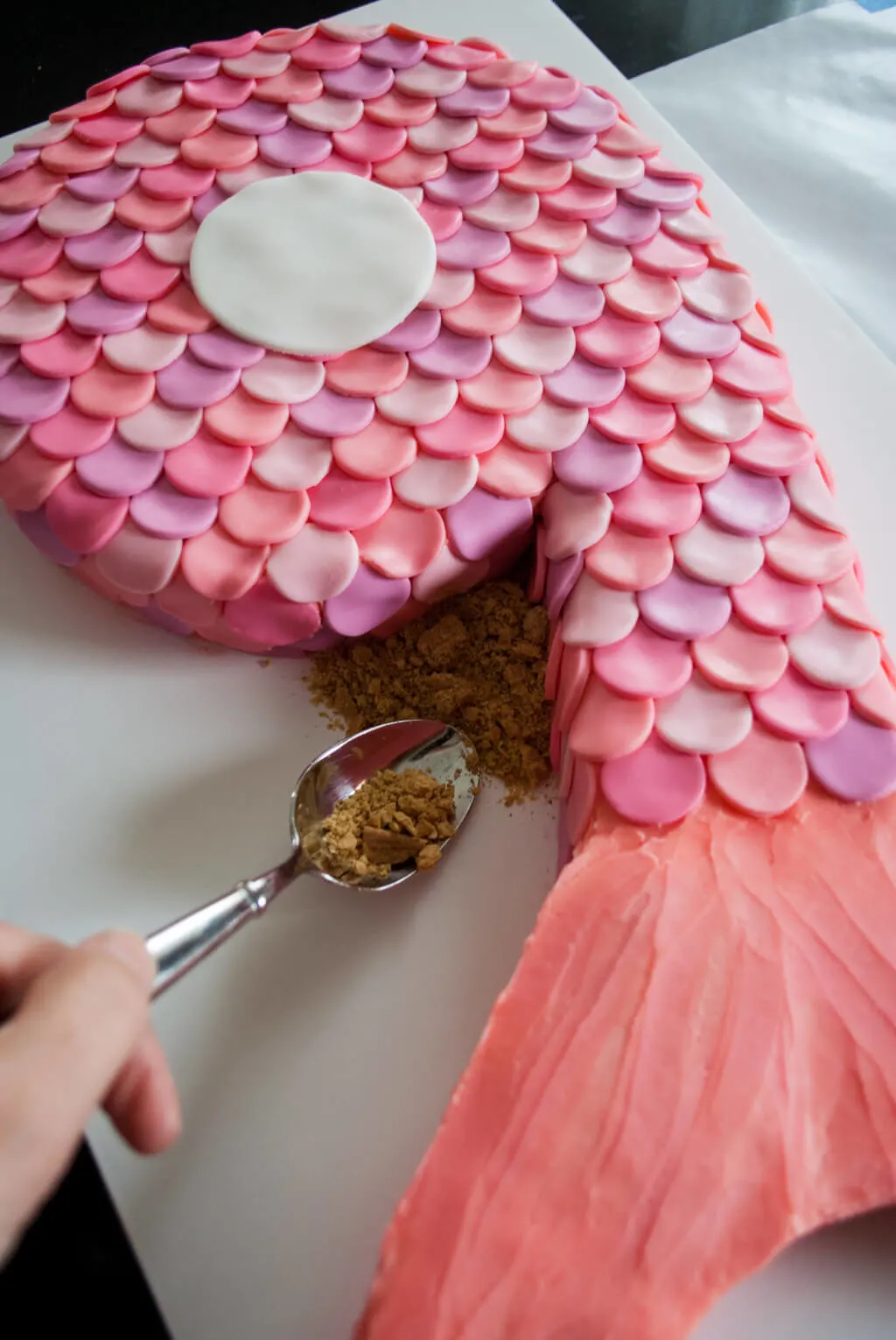 Adding edible graham cracker sand to a mermaid birthday cake