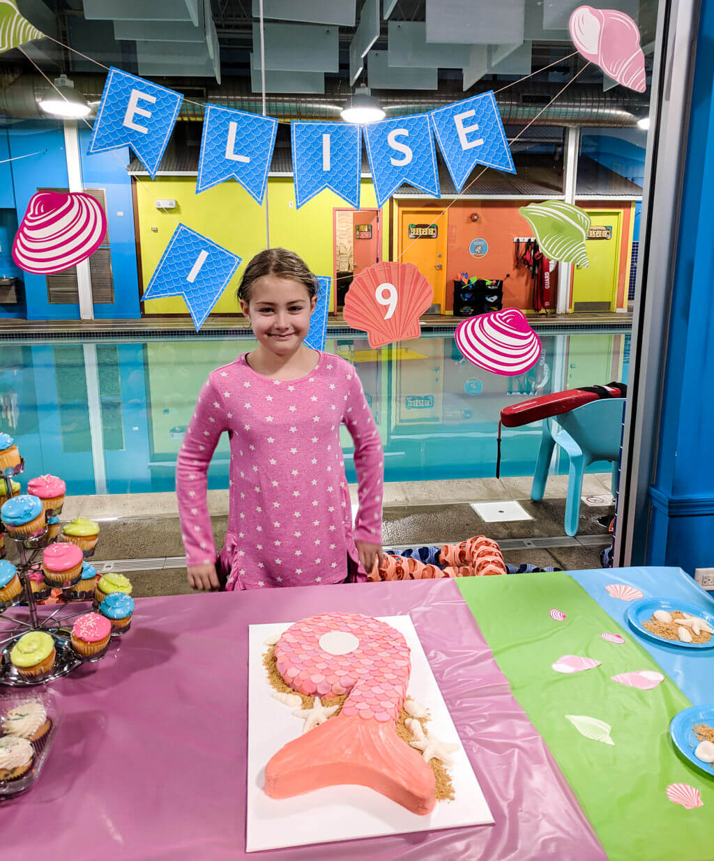 Elise with mermaid birthday cake and happy birthday banner