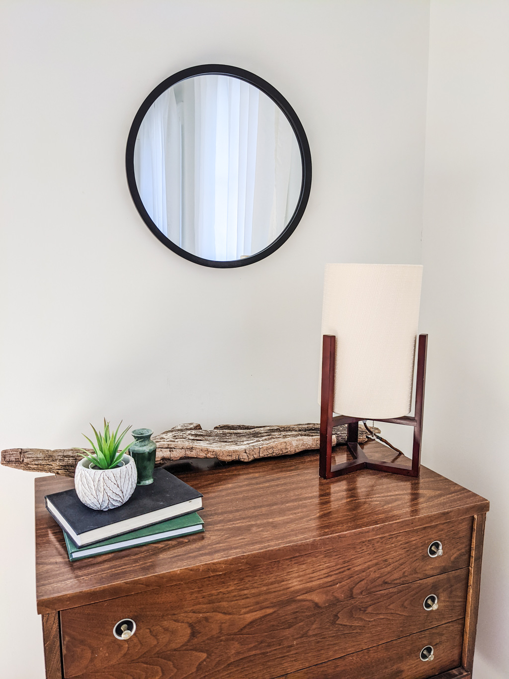 Mid-century modern desk lamp and round mirror on a vintage dresser