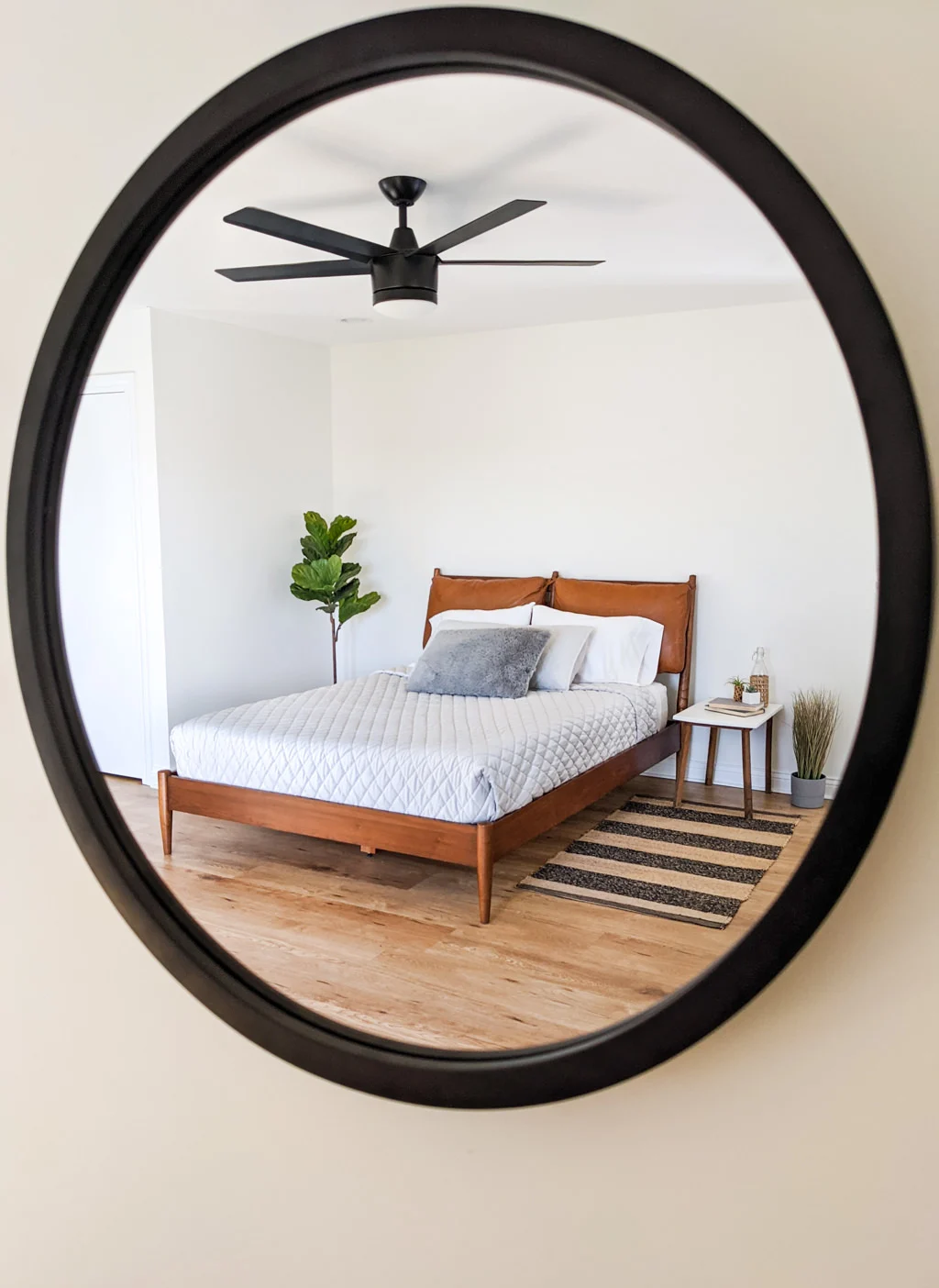 Round mirror reflection of a mid-century modern bedroom style