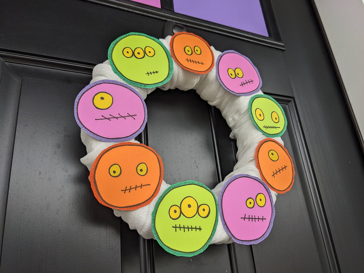 DIY Halloween Monster Wreath in purple, green, and orange on a black front door