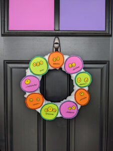 DIY Halloween Monster Wreath in purple, green, and orange on a black front door