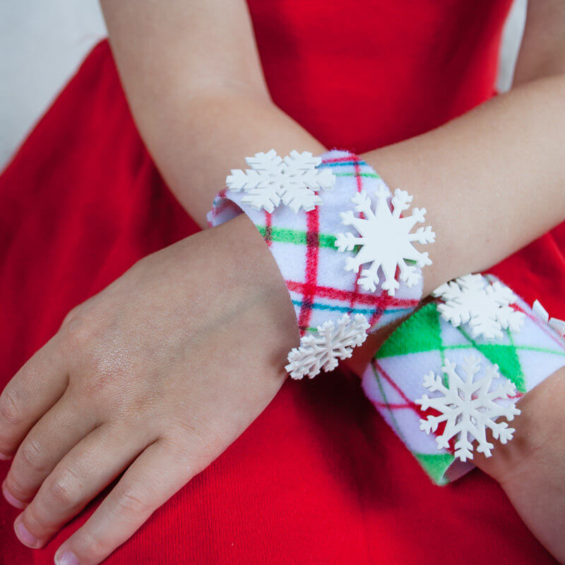 No-sew DIY Christmas bracelets craft for kids. Color any pattern or holiday scene that you wish, and make optional Shrinky Dink snowflakes to dress it up. #christmascrafts #christmas #DIYforkids #handmadechristmas #kidsactivities