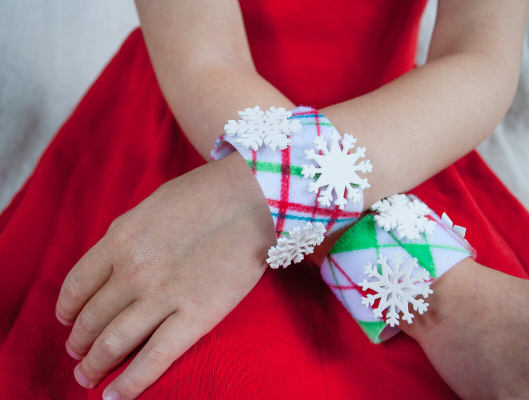 No-sew DIY Christmas bracelets craft for kids. Color any pattern or holiday scene that you wish, and make optional Shrinky Dink snowflakes to dress it up. #christmascrafts #christmas #DIYforkids #handmadechristmas #kidsactivities 