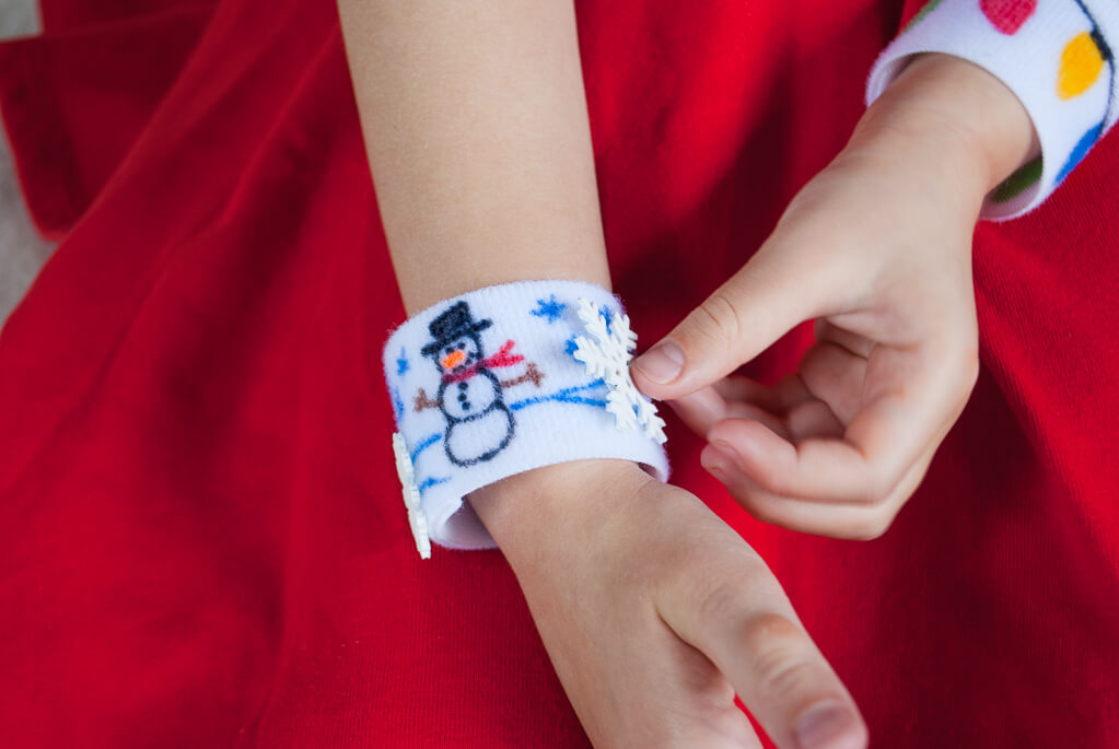 DIY no-sew Christmas bracelets for kids colored using fabric markers. Kids can move around the Shrinky Dink snowflakes as they wish. #christmasgifts #handmadechristmas #diy #diychristmas #kidsactivities
