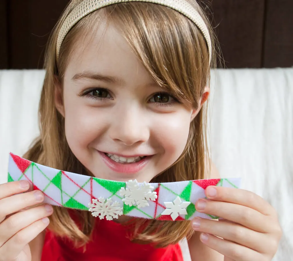 No-sew DIY Christmas bracelets craft for kids. Color any pattern or holiday scene that you wish, and make optional Shrinky Dink snowflakes to dress it up. #christmascrafts #christmas #DIYforkids #handmadechristmas #kidsactivities 